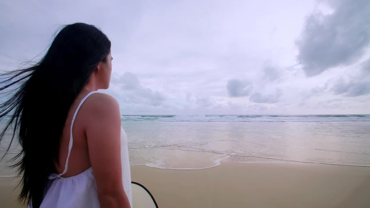 4K背景美女站在海滩上与海外的日落。快乐的女游客站在沙滩上，放松地欣赏日落。普吉岛，泰国自由天堂海滩。夏天假期的假期视频素材