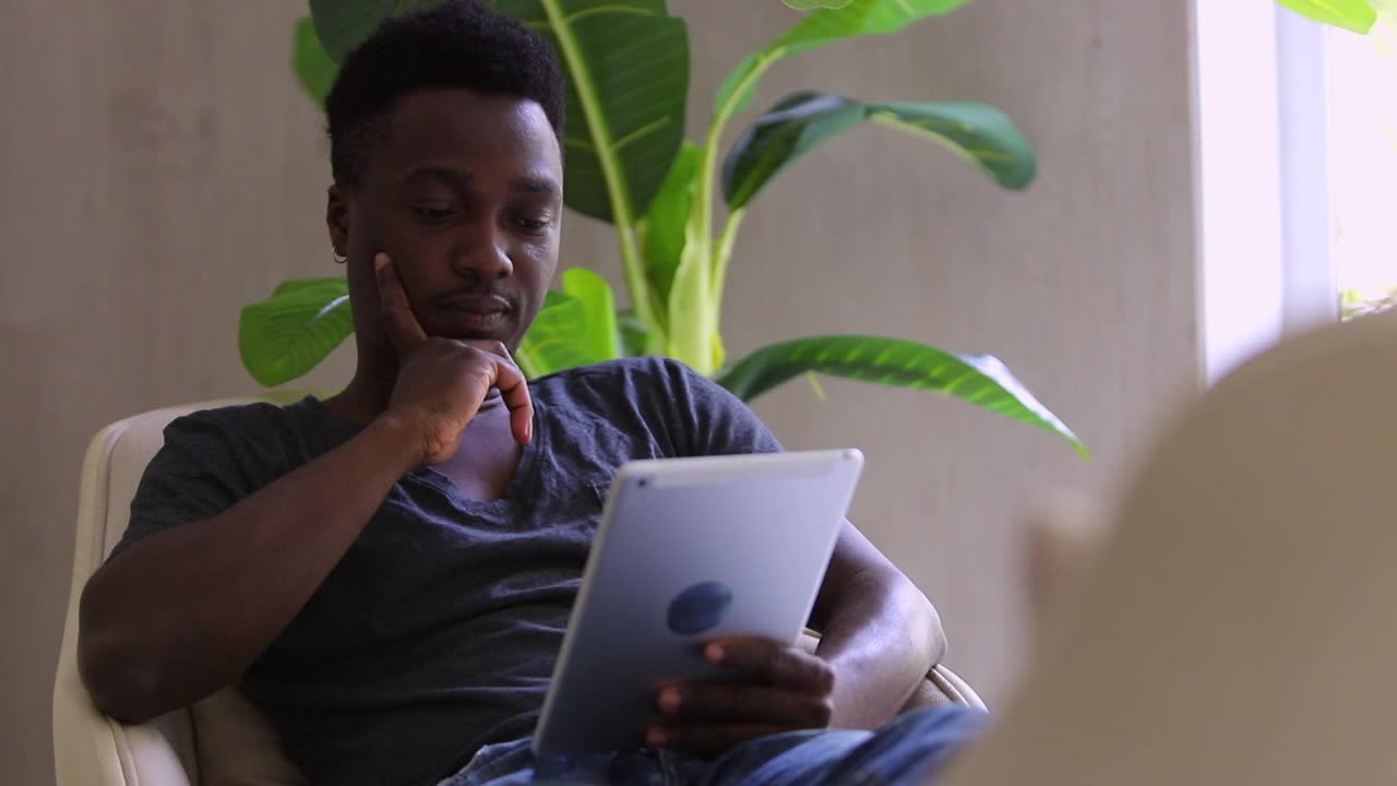 深思熟虑的聪明黑人男性阅读电子书，点头和思考Spbi。在家使用平板电脑视频素材