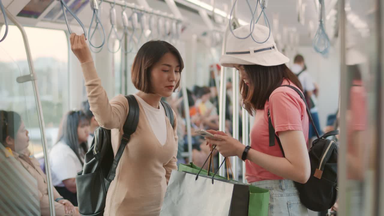 两个亚洲女人在火车上使用智能手机聊天，慢动作视频素材