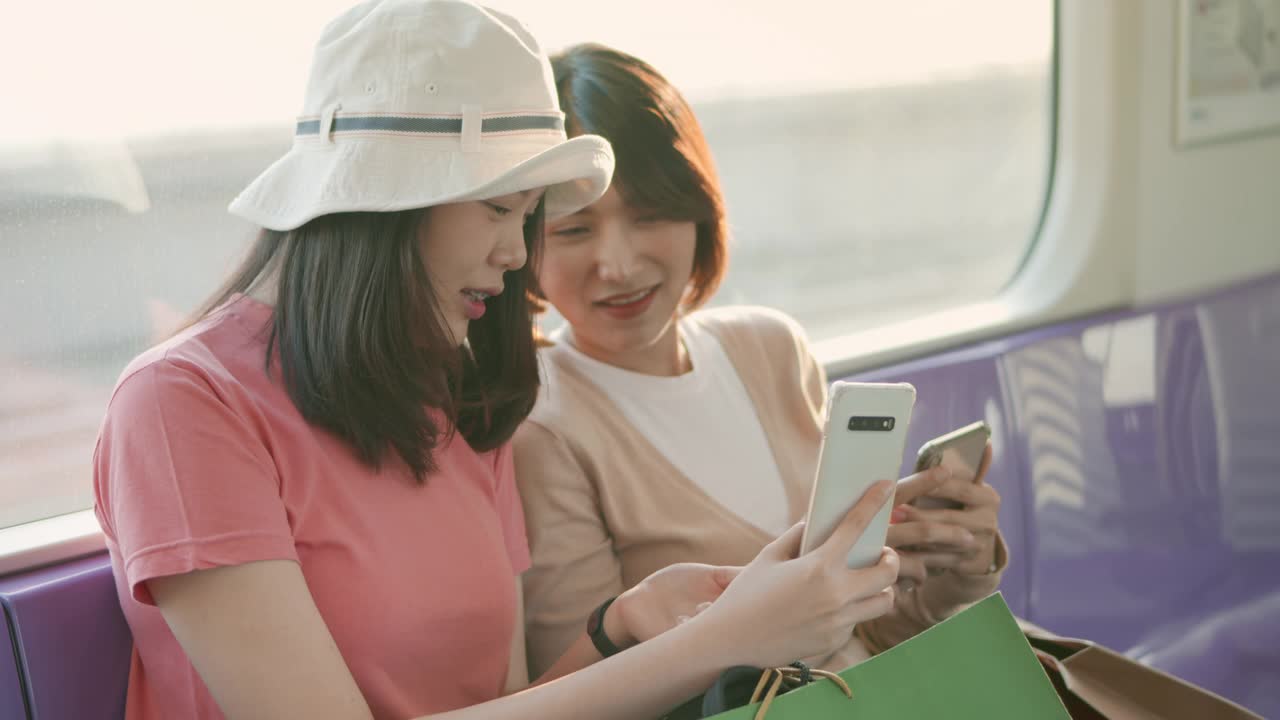 两个亚洲女人在火车上使用智能手机聊天，慢动作视频素材