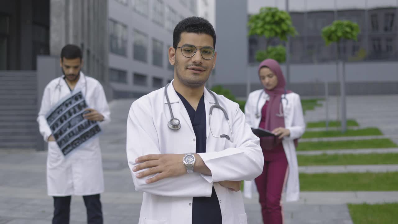 阿拉伯医生，双手交叉站在户外，带领多民族医疗队视频素材