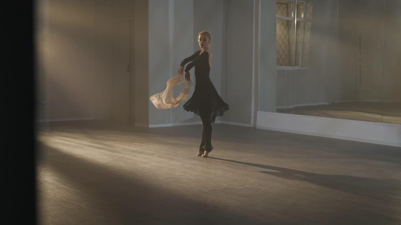 苗条的天才芭蕾舞女演员在芭蕾舞工作室背光下带着米色围巾排练舞蹈的广角镜头。勤奋的芭蕾舞者在室内跳舞。表演和编舞的概念。视频素材
