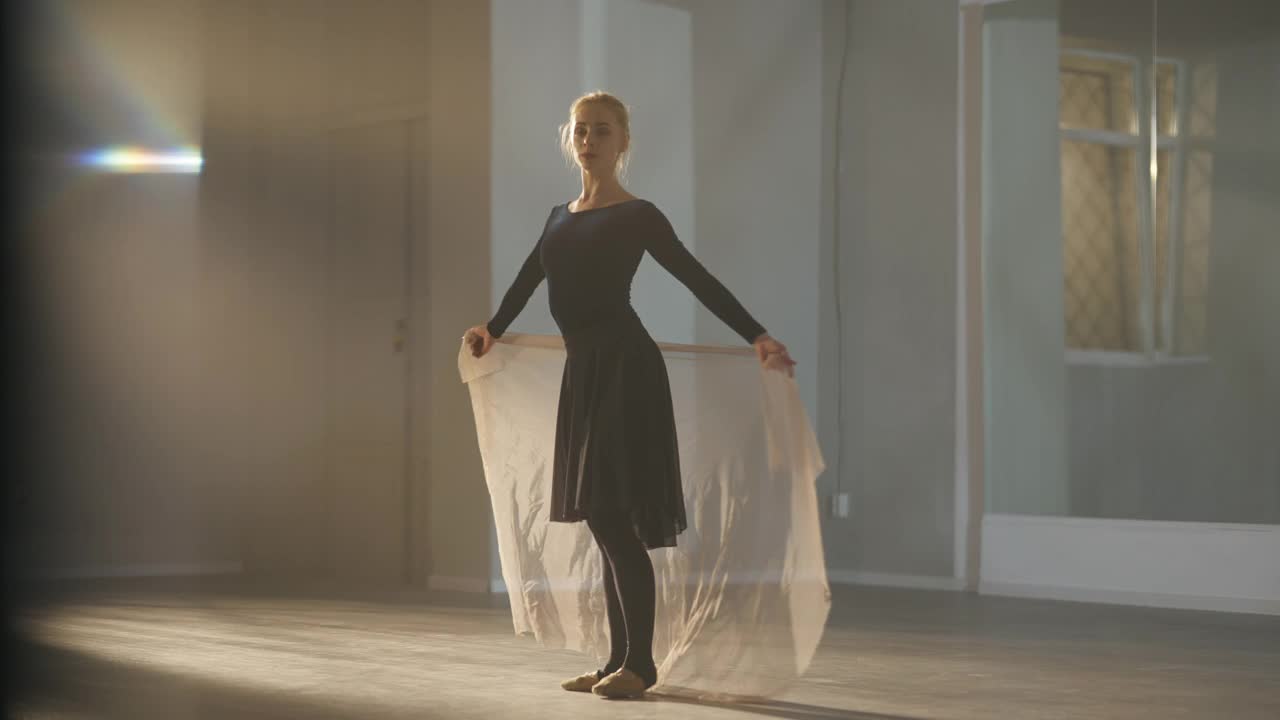宽镜头才华横溢的苗条美丽的白人芭蕾舞女演员与优雅的围巾在雾中跳的慢动作。优雅熟练的女芭蕾舞者的肖像在背光室内排练。视频素材