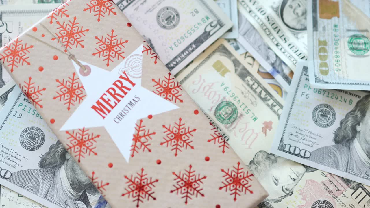 圣诞红礼品盒上印有美元钞票背景。节日礼品概念视频素材