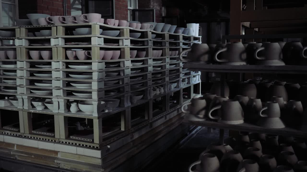 在生产车间的一间黑暗的房间里，架子上摆满了五颜六色的陶瓷盘子视频素材