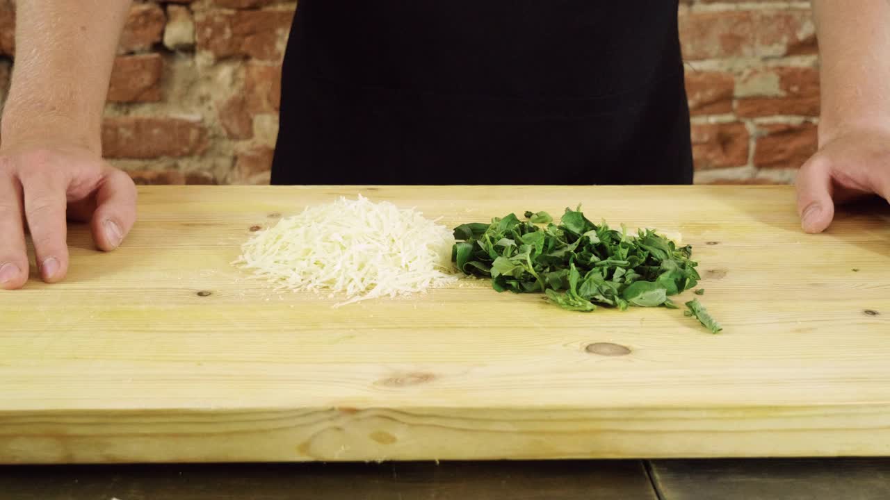 香蒜沙司的准备。帕尔马干酪，切碎的罗勒放在砧板上。4 k视频下载