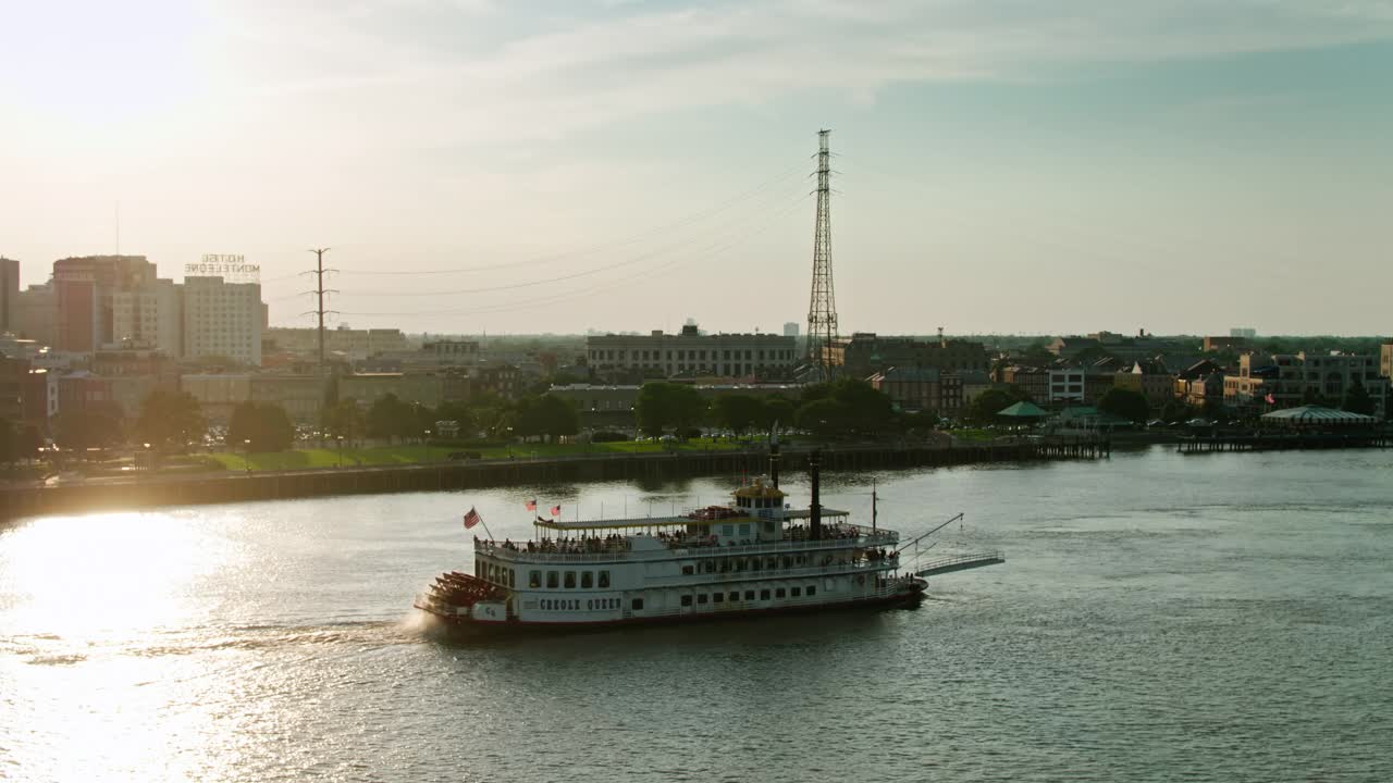 日落时分，无人驾驶飞机在观光船旁飞过新奥尔良法国区视频下载