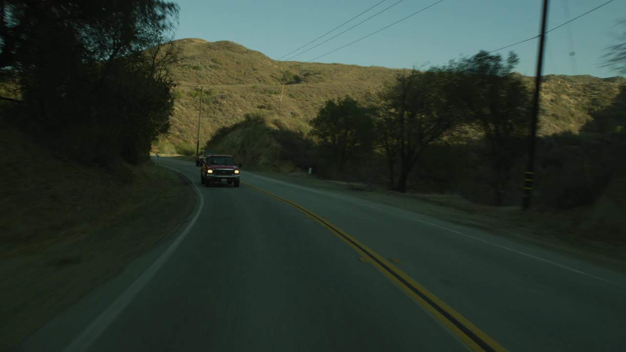 加工板直背的汽车行驶在农村地区或乡村道路上。干燥的山坡和电线杆清晰可见。山脉部分可见在bg。可能是山路。木栅栏可见。视频素材