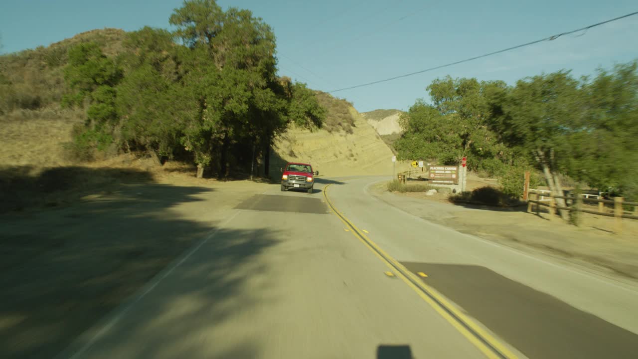 加工板直背的汽车行驶在农村地区或乡村道路上。干燥的山坡和电线杆清晰可见。山脉部分可见在bg。可能是山路。木栅栏可见。可能是农田。视频素材