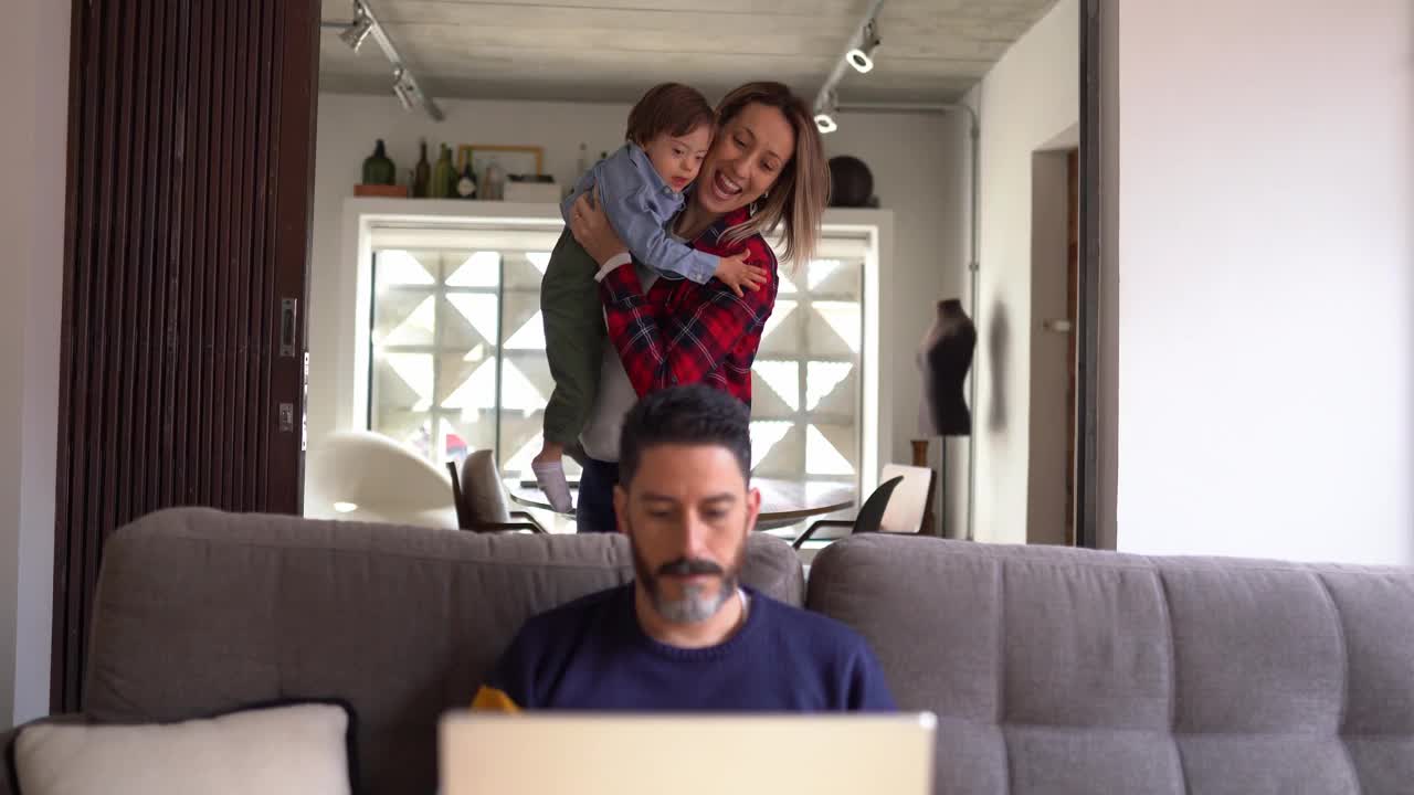 男人使用笔记本电脑，妻子和特殊需要的儿子回家视频下载
