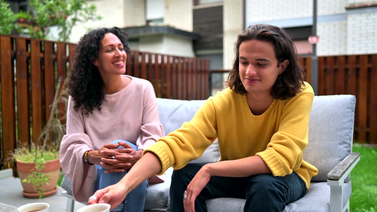 中年西班牙裔妇女和年轻西班牙裔男子在户外喝咖啡和吃马卡龙视频下载