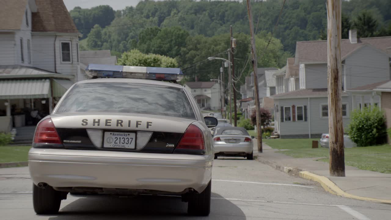 跟踪拍摄的是治安官的汽车在乡村小镇的街道上行驶。房屋可见。视频素材
