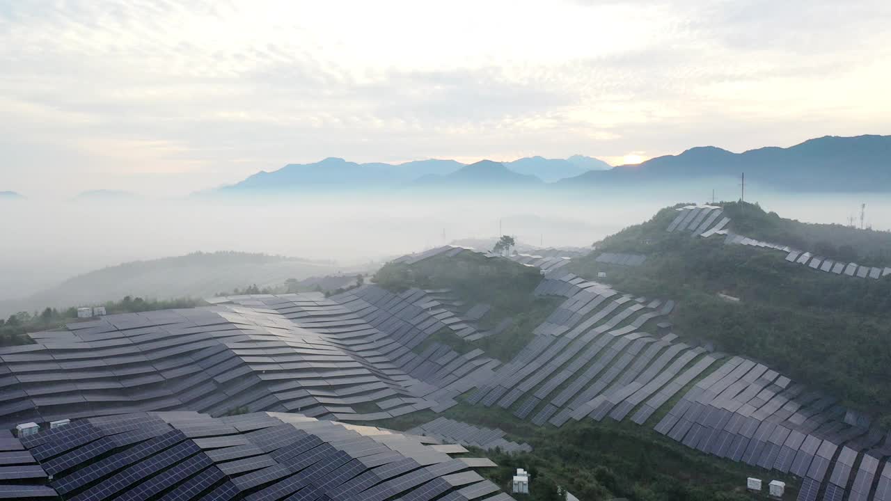在晨雾中鸟瞰山坡上起伏的太阳能发电厂视频素材