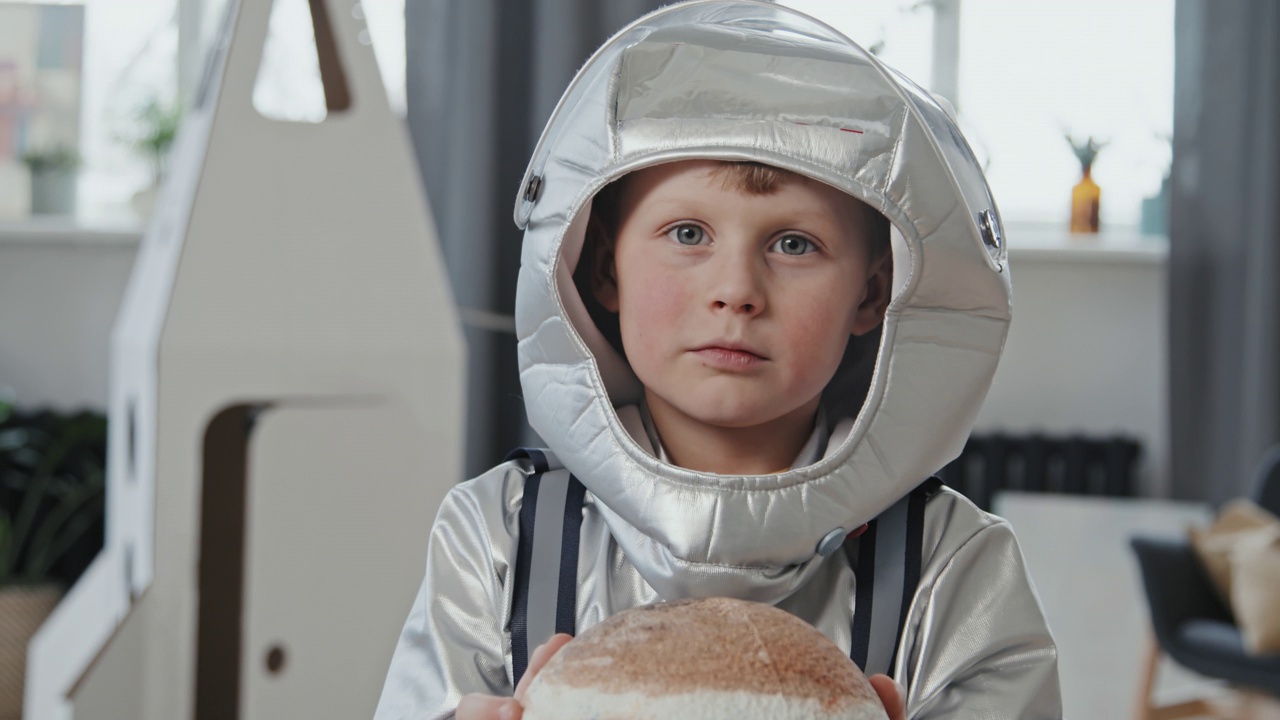 穿着太空服的可爱男孩拿着行星模型视频下载