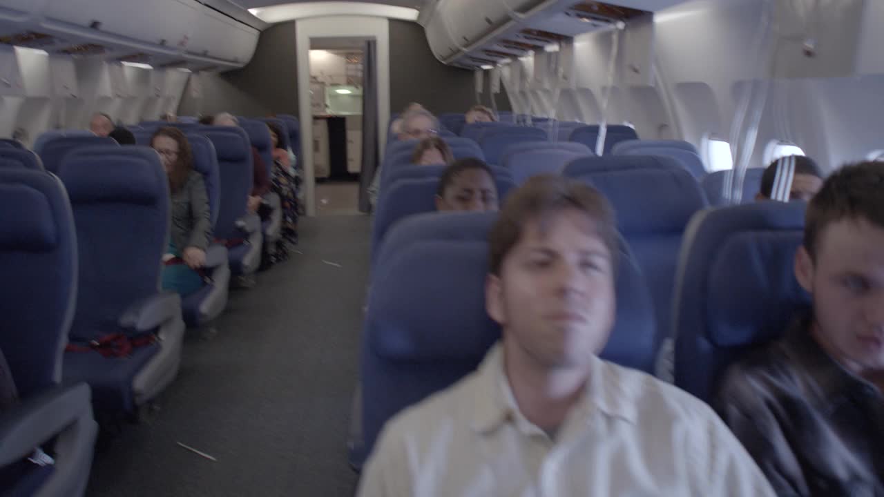 飞机颠簸时乘客的近角度。飞机摇晃，灯光闪烁。人们看起来又害怕又担心。视频下载