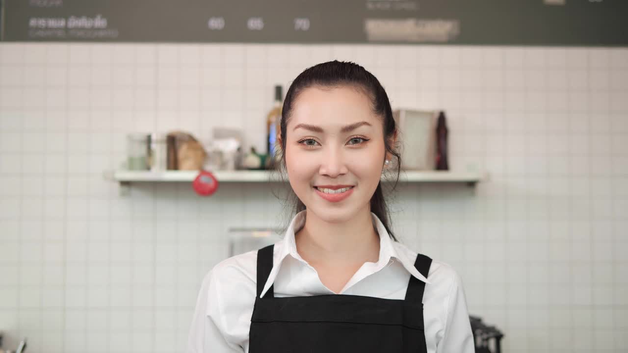 亚洲女咖啡师拿着热咖啡和面包微笑着看着镜头视频素材