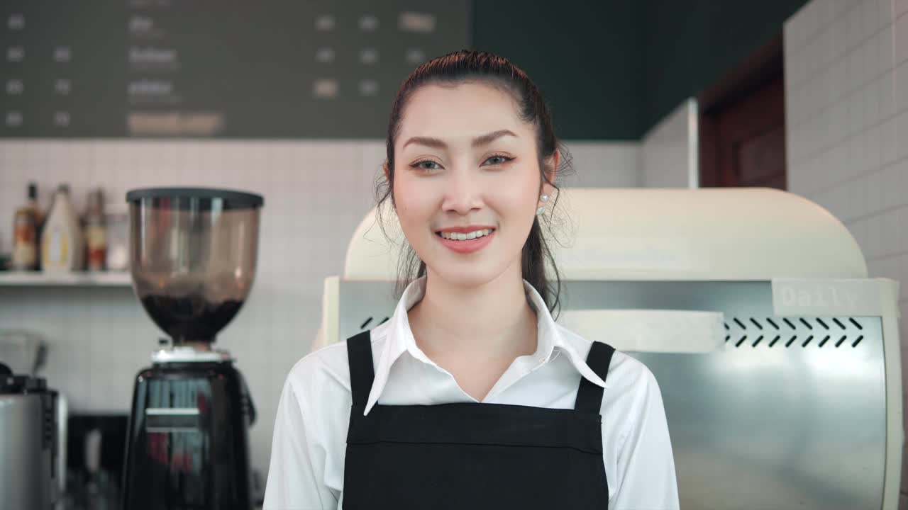 微笑的亚洲女咖啡师在咖啡店双臂交叉站立的肖像视频素材