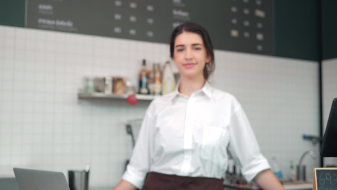 一幅女咖啡师的肖像，微笑着双臂交叉站在咖啡店的吧台上视频素材