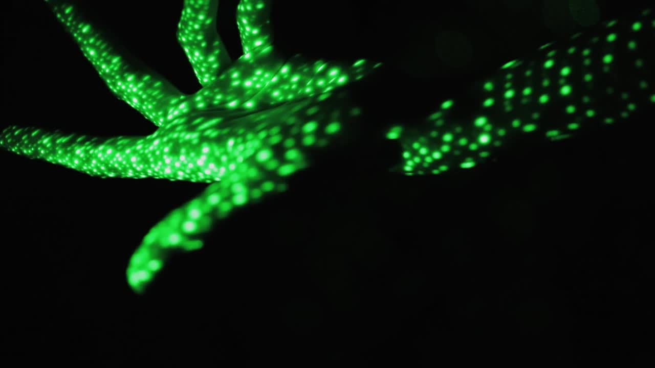 在黑色背景上抽象的绿色霓虹灯下触摸双手的全息图。视频下载