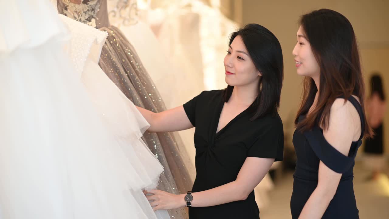 亚洲的中国女新娘和伴娘正在婚纱店为她的婚礼寻找完美的婚纱视频下载