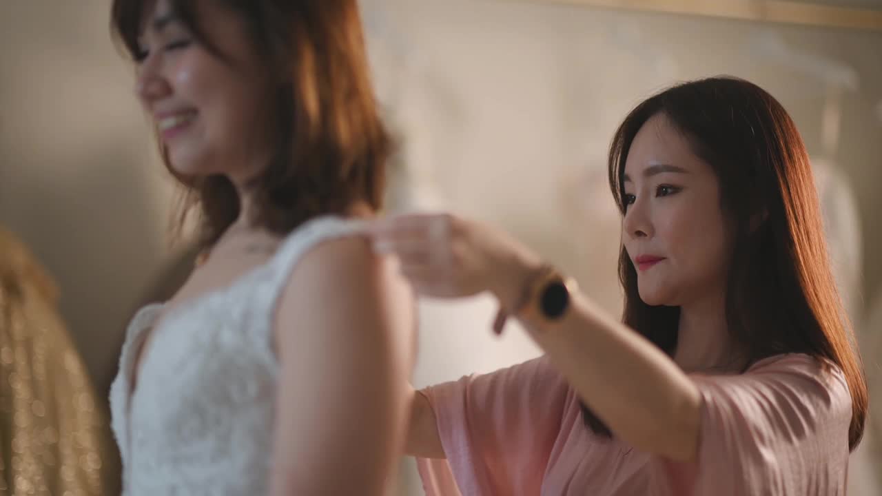 亚洲华人女婚纱店老板正在为顾客测量新娘的体型，为顾客量身定制婚纱视频下载