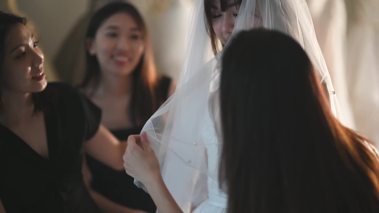 亚洲的中国新娘在婚纱店试穿婚纱，伴娘在旁边欣赏婚纱的美丽视频下载
