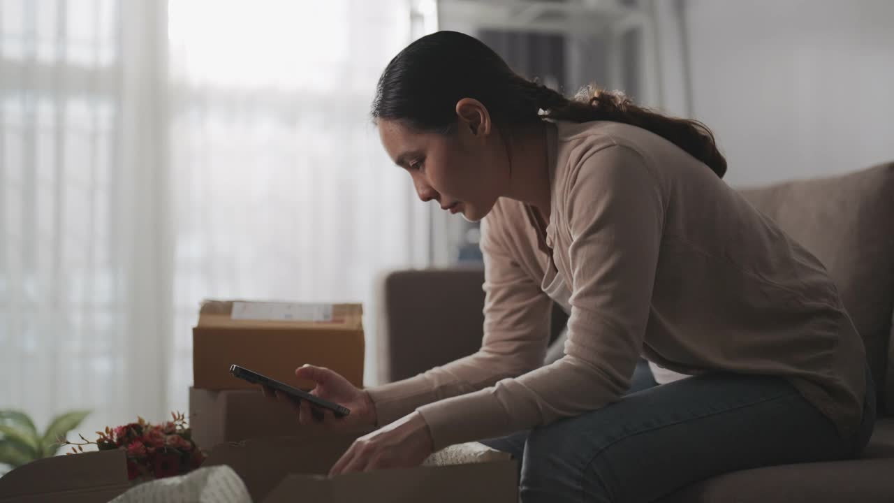 亚洲女人消费者觉得坐沙发不好，拿着电话与网店网上关于在家里订购的问题产品，抱怨视频素材