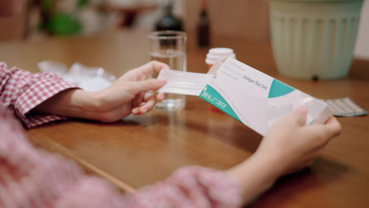 妇女在家中打开快速抗原检测试剂盒。视频下载