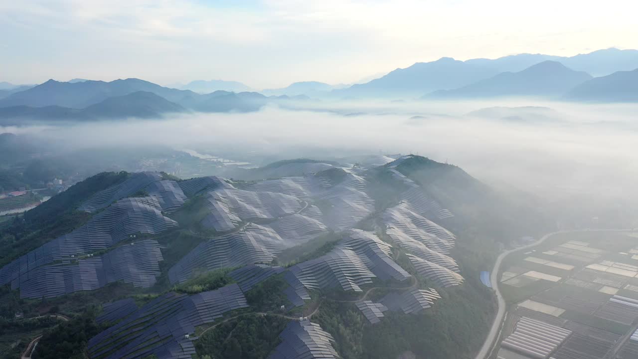 从山顶的晨雾中鸟瞰壮丽的太阳能发电站视频下载