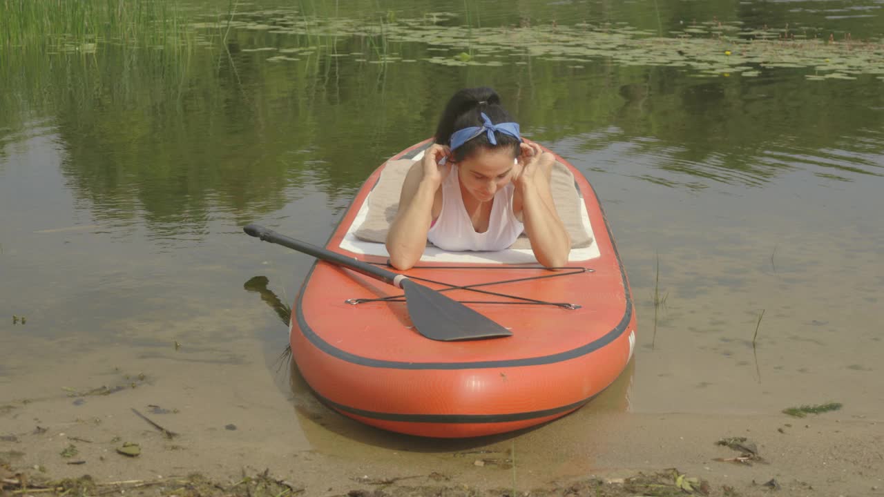 一个女人在湖边的桨板上晒日光浴视频下载