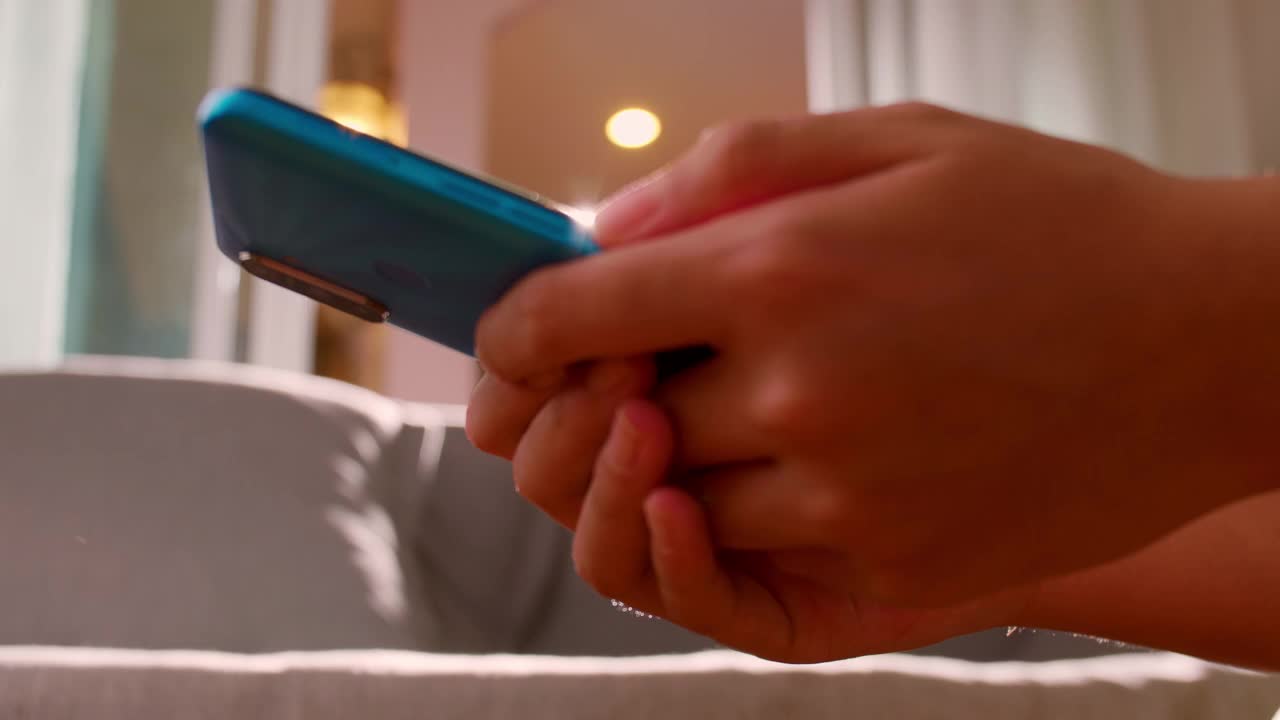 手握手机的女性在家看书打字按摩。近距离拍照的女性在家中客厅用电话聊天或发短信。技术交流的概念视频素材