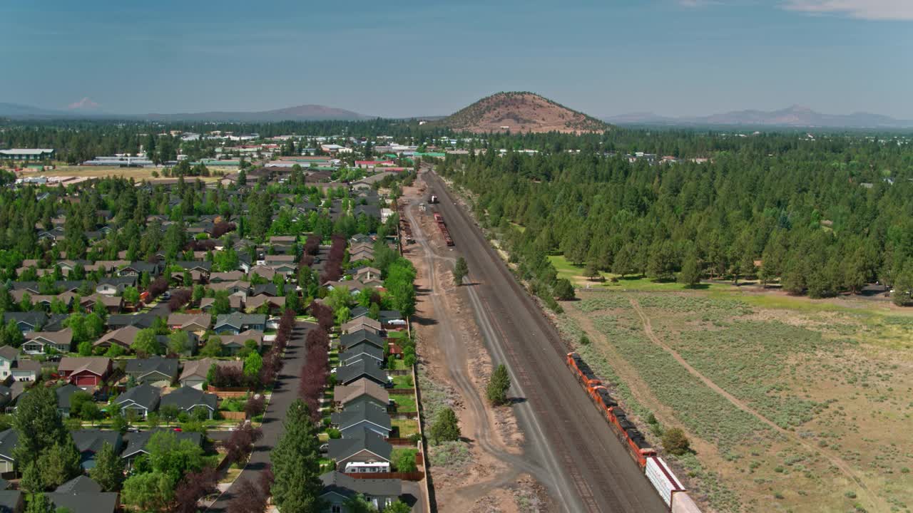 货运火车通过郊区和林地在弯曲的边缘，或-空中视频下载