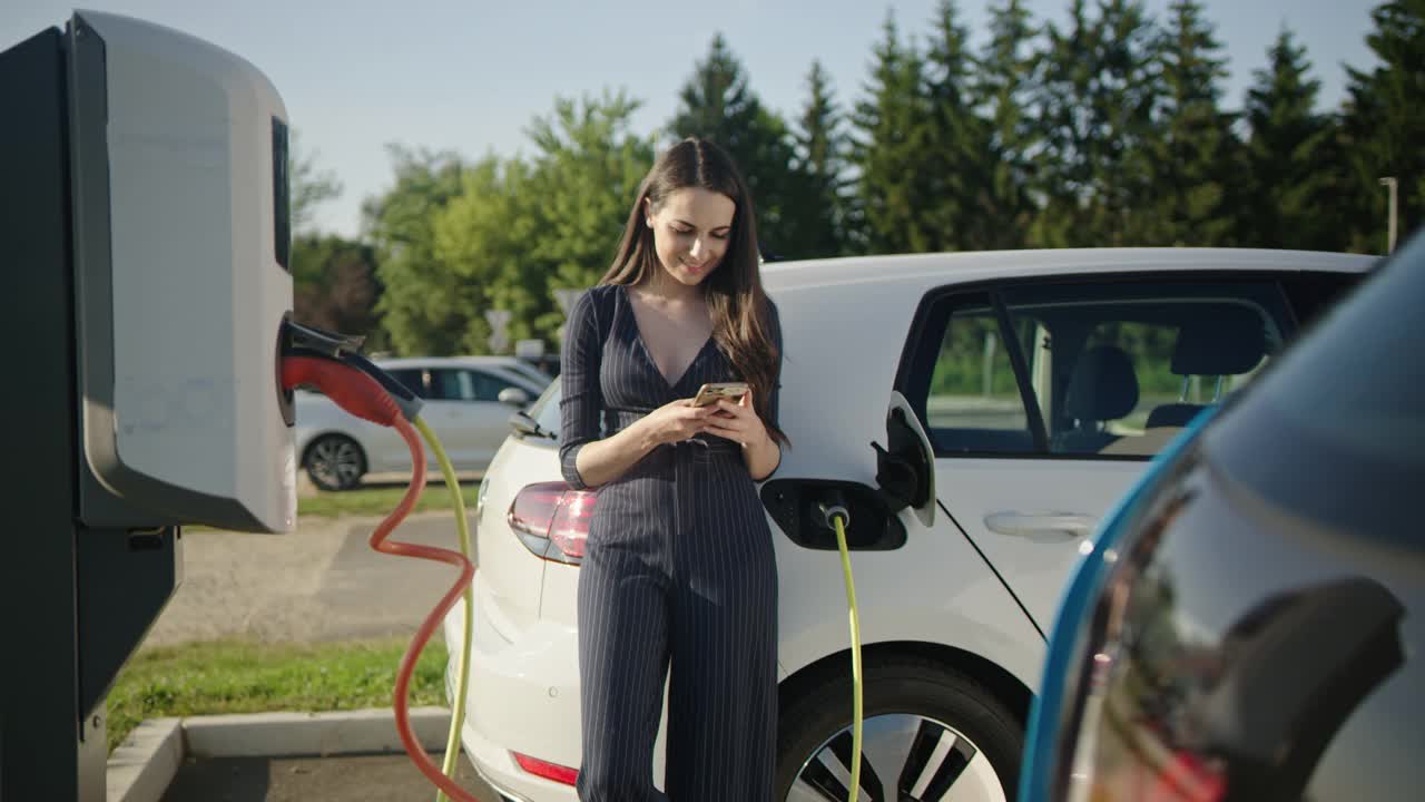 一名年轻女子在停车场充电时使用智能手机视频下载