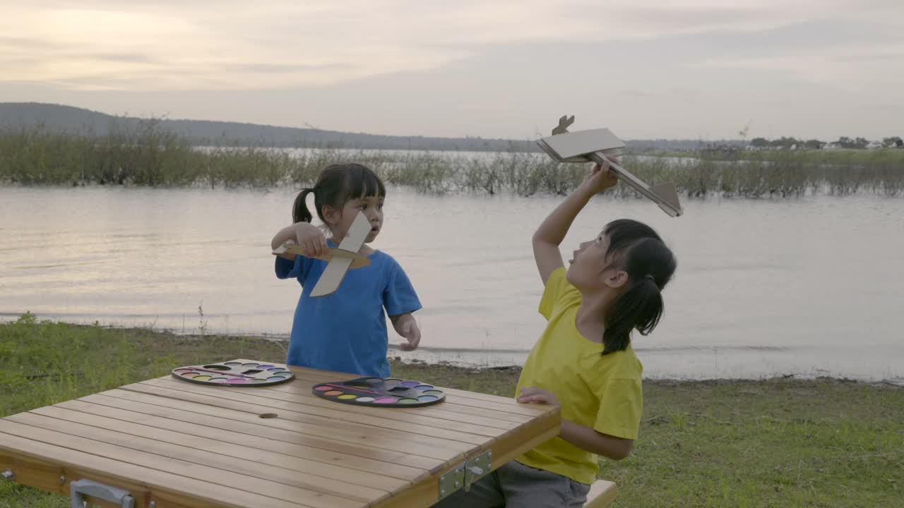兄弟姐妹在夕阳下玩木飞机的场景，谁想追随梦想视频素材