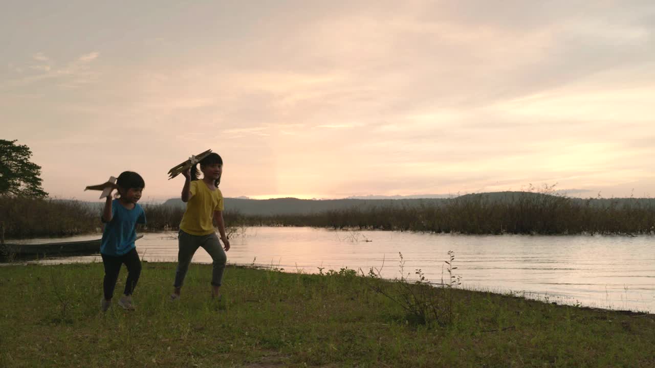 夕阳下兄弟姐妹玩木飞机的场景慢镜头，谁想追随梦想视频素材