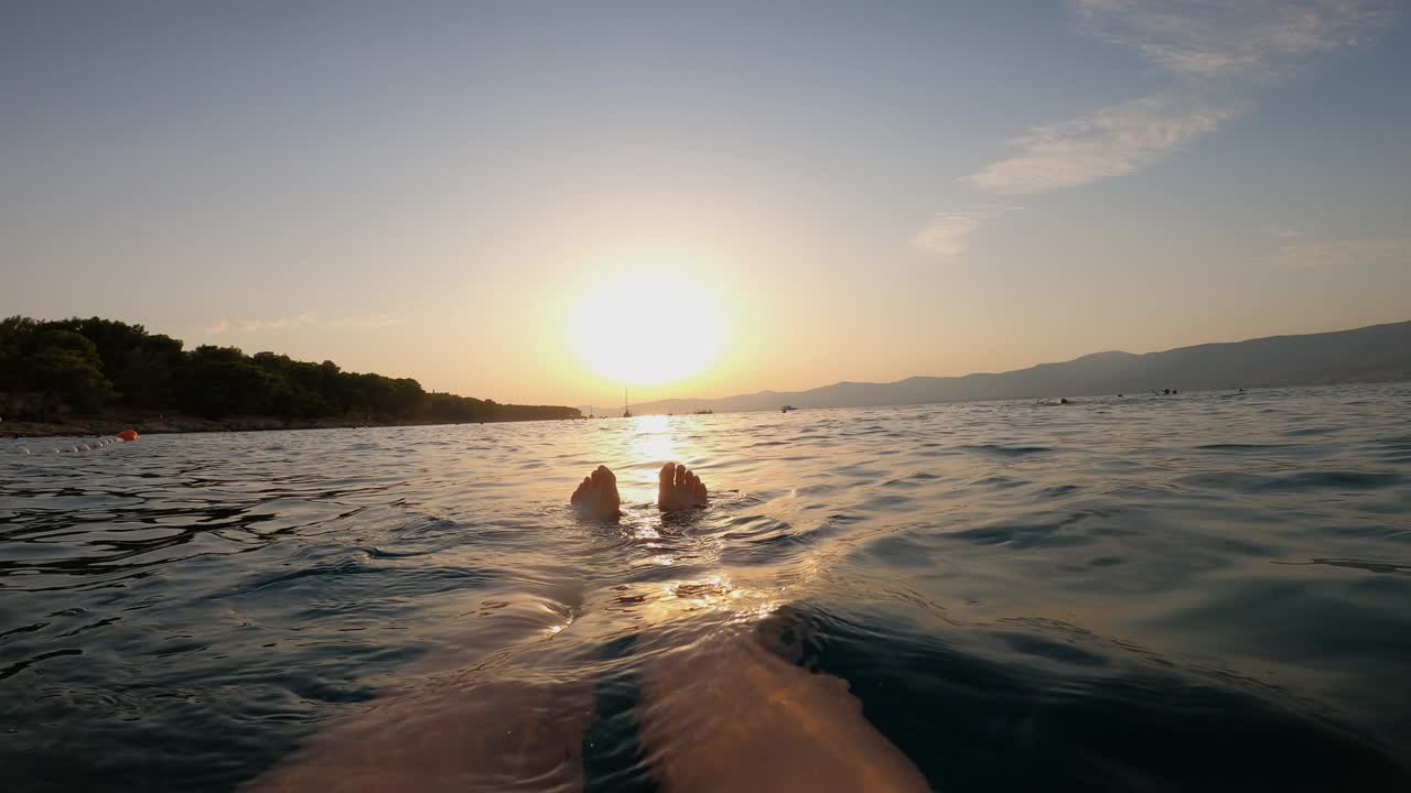 女人漂浮在亚得里亚海的水面上，在海上看日落视频下载
