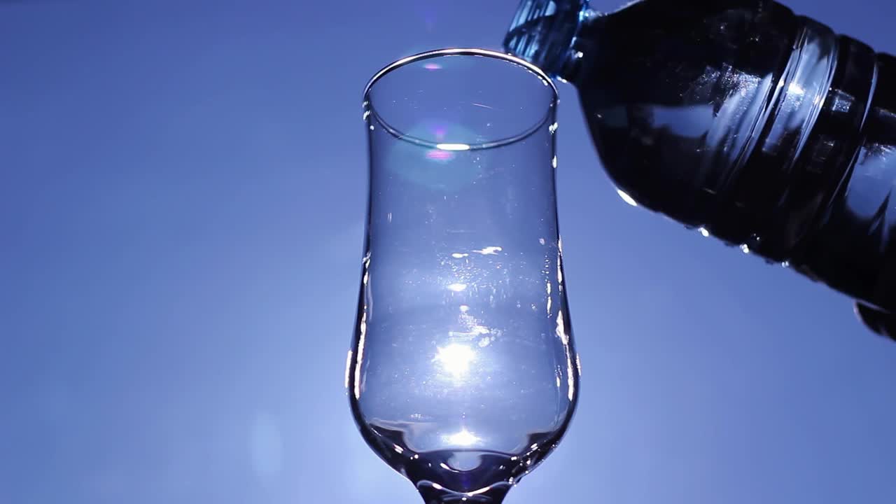 把新鲜的饮用水倒进玻璃，蓝天映衬视频素材