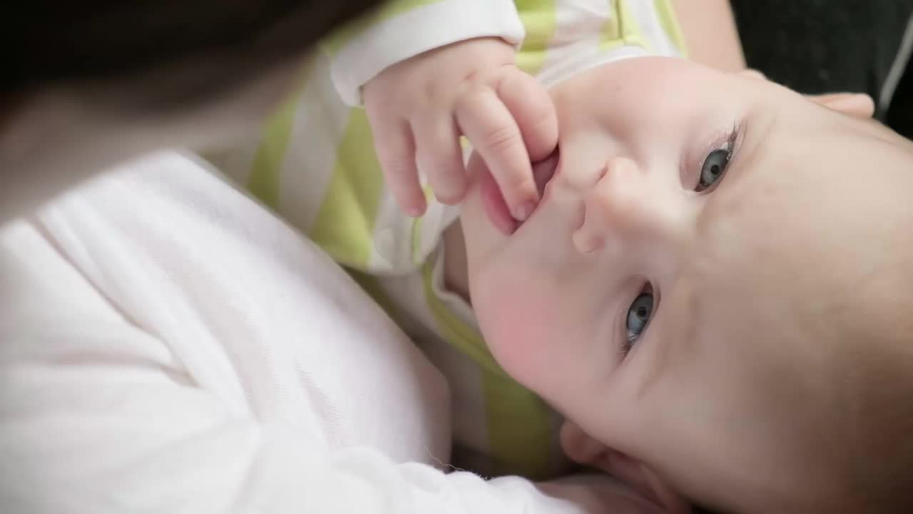 一个美丽的婴儿的特写肖像在白色。头和脸。刚出生的婴儿侧躺着，看着摄像机。母亲，健康，儿科概念。可爱可爱视频素材