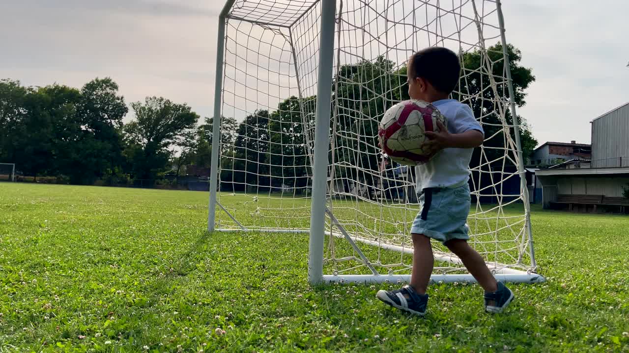 一个小男孩在足球场上玩耍视频下载