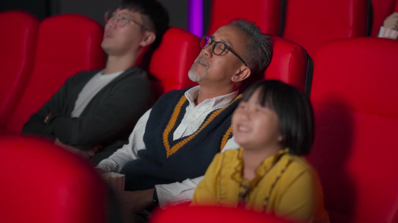一位亚裔中国老人和他的孙女在电影院看电影睡着了视频素材