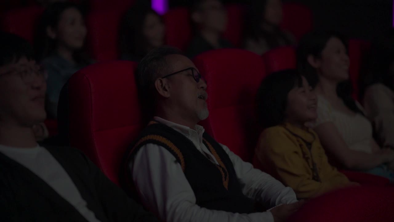 一位亚裔中国老人和他的孙女在电影院看电影睡着了视频素材