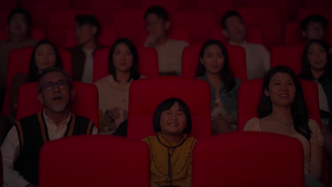 一位活跃的亚洲华人老人和他的孙女笑着在电影院看电影视频素材