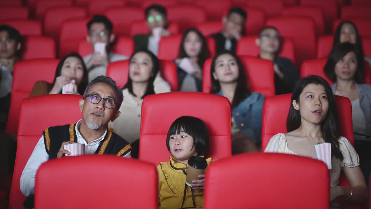 一位活跃的亚洲华人老人和他的孙女喜欢在电影院看电影视频素材