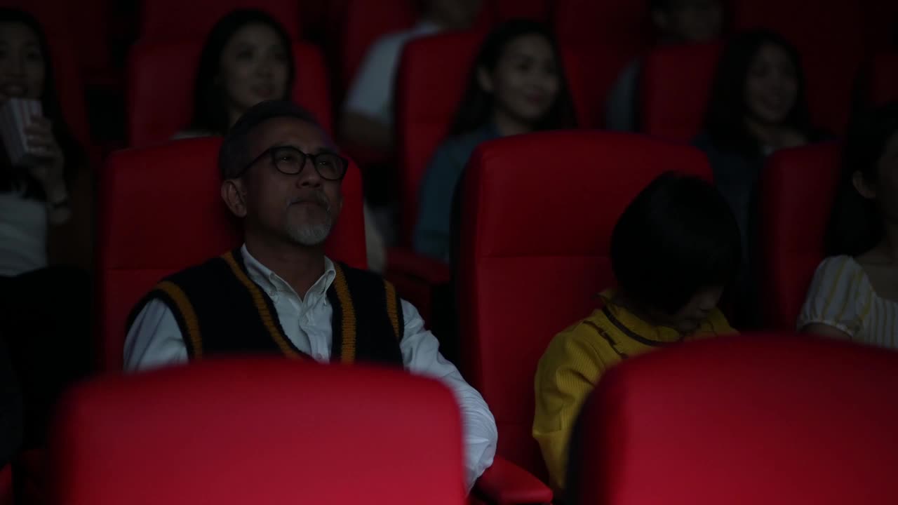 一位亚裔中国老人和他的孙女在电影院看电影时睡着了视频素材