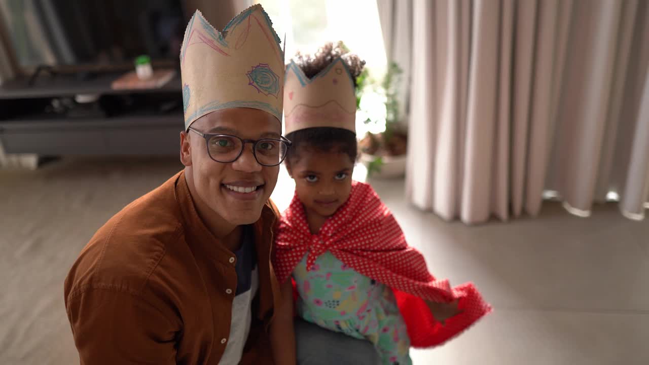 父亲和女儿在家里戴着皇冠玩耍的肖像视频素材
