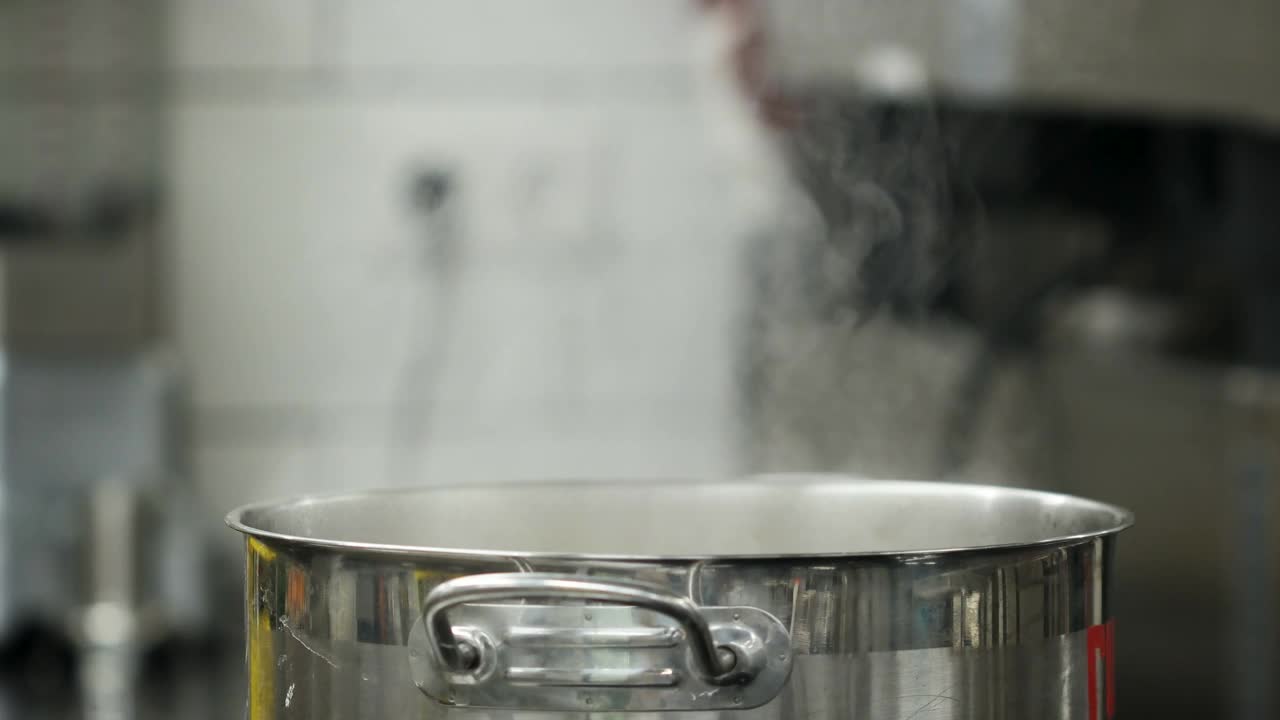 蒸汽从炉子上锅里的沸水中升起。媒体。蒸汽和白烟在专业的厨房背景上升起。煮的时候从锅里蒸出来。慢动作烹调过程。视频下载