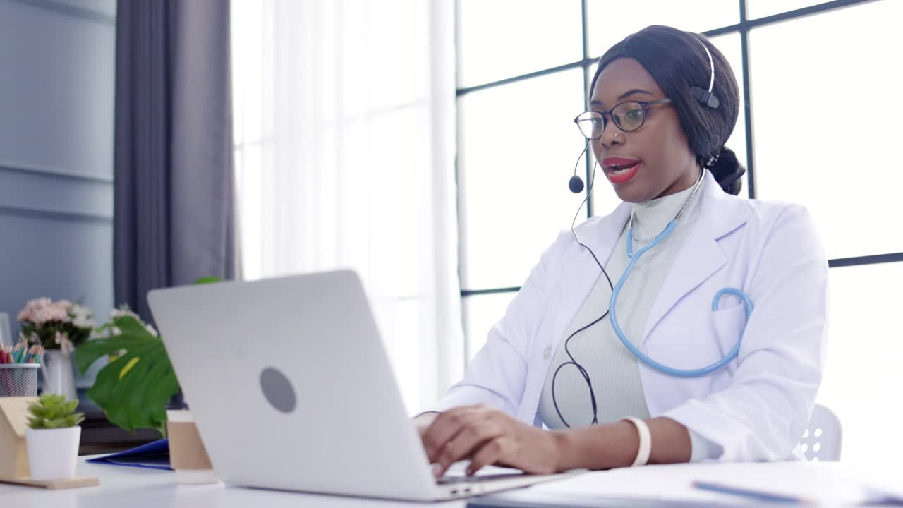 非裔美国医生戴着耳机在医院视频通话服务与远程病人通话。医疗咨询。与同事进行网络研讨会。远程保健和远程医疗概念。视频素材
