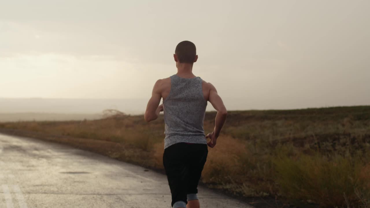 自信的男运动员在雨中奔跑，向后看，慢动作。自我发展与运动成就。适合健身模型男人锻炼生活健康的生活方式马拉松训练视频素材