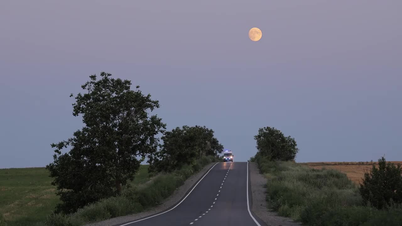 救护车在夜间行驶在通往村庄的公路上。开着信号灯的救护车视频素材