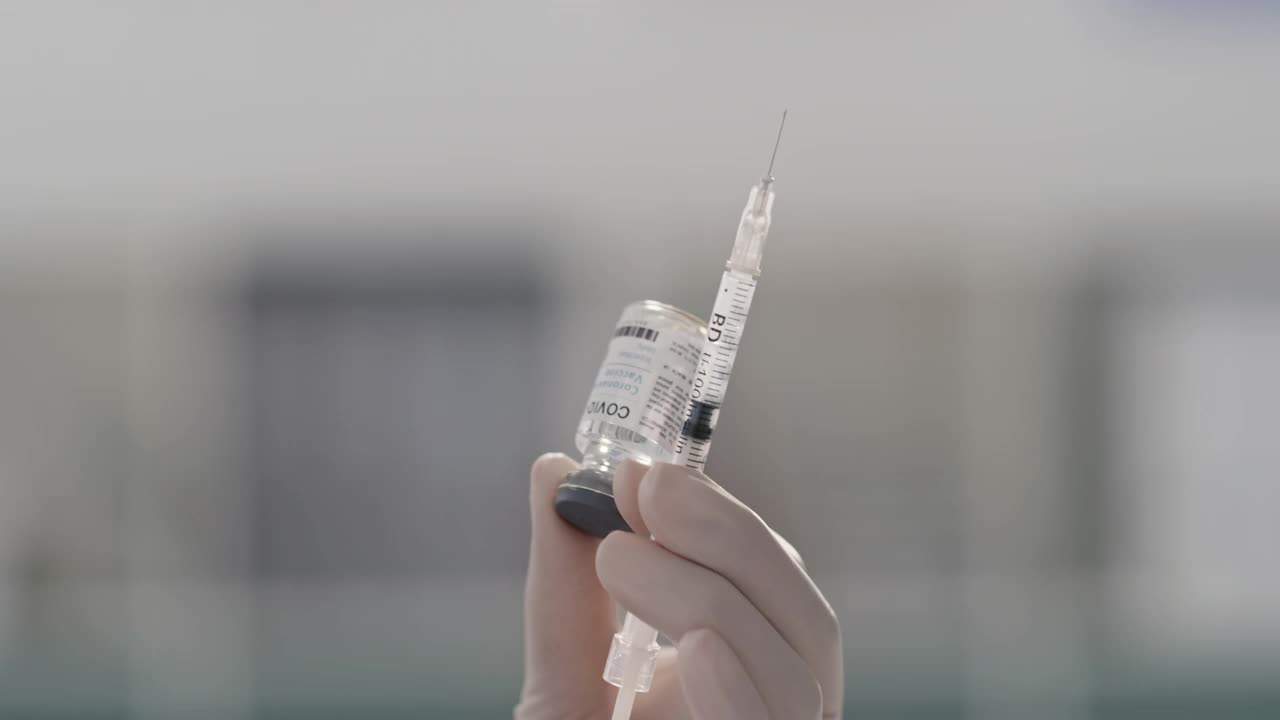 一段4k视频记录了一名面目模糊的医护人员在工作时用注射器从管子中抽取液体的过程视频素材